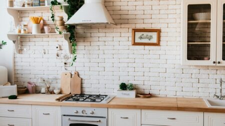 a kitchen with stove, counters, cutting boards, and shelves